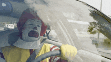 a mcdonald 's clown is driving a car