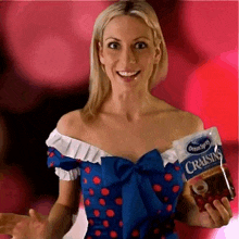 a woman in a blue dress is holding a bag of cranberries .