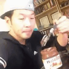 a man is holding a jar of nutella in his hand .