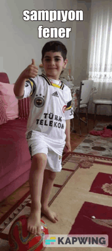 a young boy wearing a turk telekor shirt giving a thumbs up