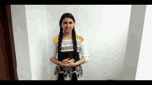 a woman with long braids is standing in front of a white wall .