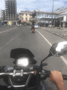 a person riding a motorcycle down a street with a honda logo on the handlebars