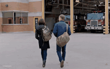 a man and a woman are walking in front of a fire truck number 81