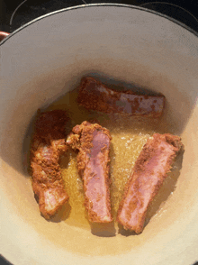 ribs are being cooked in a pot of oil on a stove