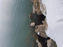 a snowy rocky shoreline with a body of water in the background