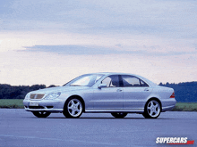 a silver mercedes is parked on a road with supercars.com in the corner