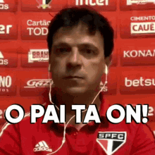 a man wearing headphones and a red shirt with the words `` o pai ta on '' on it .