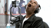 a man wearing headphones is singing into a microphone while looking up at the sky