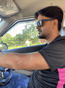 a man wearing sunglasses and a black shirt driving a car