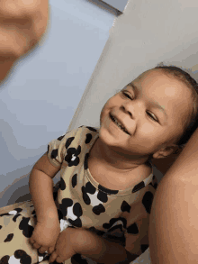 a baby in a leopard print dress smiles for the camera