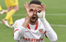 a soccer player wearing a white marathon jersey makes a funny face