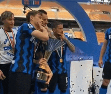 a group of soccer players holding a trophy with one wearing a shirt that says ' smiley 1952 ' on it