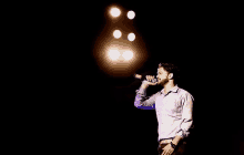 a man is singing into a microphone in a dark room