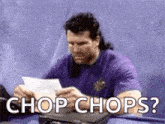 a man in a purple shirt is sitting at a table looking at a piece of paper and says `` chop chops '' .