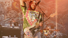 a man in a tie dye shirt playing a guitar