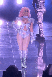 a woman with pink hair is standing on a stage in front of a man