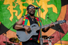 a man singing into a microphone while holding a guitar that says epiphone