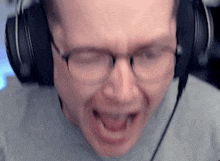 a man wearing glasses and headphones is making a face .