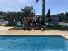 a group of men are posing for a picture next to a pool