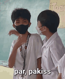 two boys wearing face masks are standing next to each other in a classroom and one of them says par pakiss .