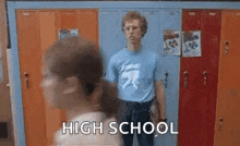 a man in a blue shirt is standing in front of a row of lockers in a locker room .