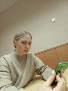 a girl sitting at a table with a green phone in her hand