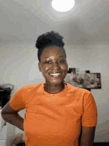 a woman wearing an orange t-shirt is smiling for the camera