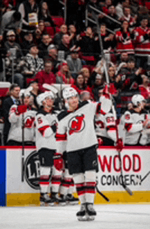 a hockey player is standing on the ice with his arms in the air