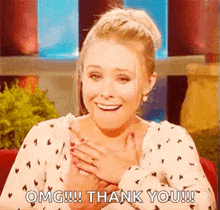 a woman is holding her hands to her chest and smiling while saying `` thank you '' .