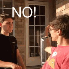 two young men are standing next to each other in front of a door with the word no written on it .