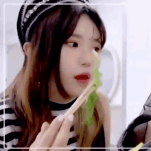 a woman is eating a salad with chopsticks while wearing a headband .