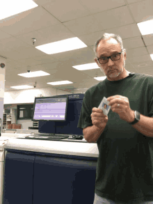 a man in a green shirt holds a card in front of a machine that says ' epson 280 ca ' on it