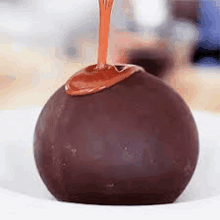 a chocolate ball with caramel being poured on it .