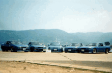 four blue cars are parked next to each other on a runway