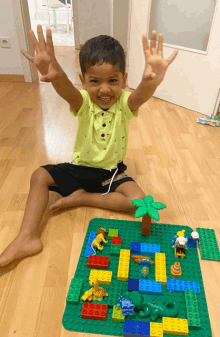 a young boy is sitting on the floor playing with lego