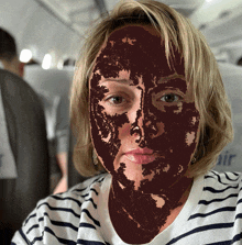 a woman wearing a striped shirt has a brown face painted on her face