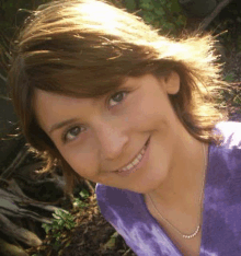 a close up of a woman 's face wearing a purple shirt and smiling .