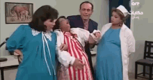 a group of people are standing around a pregnant woman being carried by a man .