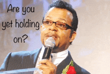 a man speaking into a microphone with the words " are you yet holding on " above him