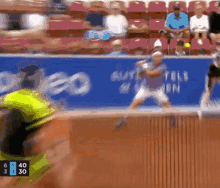 a tennis player is swinging a racket at a tennis ball while a scoreboard shows the score of the match