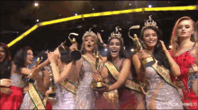 a group of women are posing for a picture and one of them is wearing a sash that says miss grand international