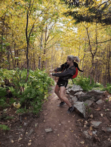 a woman with a backpack is walking down a trail