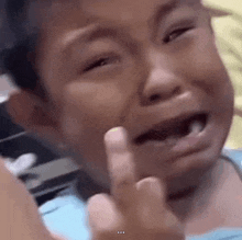 a little boy is crying and giving the middle finger to someone .