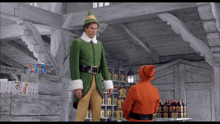 a man in a green elf costume is standing next to a man in an orange santa suit