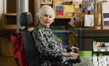 an elderly woman in a wheelchair is sitting in front of a counter with a sign that says ' pharmacy ' on it