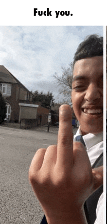 a young boy is giving the middle finger to the camera while smiling .