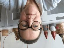 a woman wearing glasses is upside down in front of a shelf