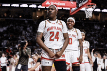 a maryland basketball player stands in front of a state farm sign