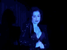 a woman in a red dress is dancing in a dark room with blue lights behind her .