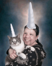 a woman is holding a cat with a unicorn horn on her head